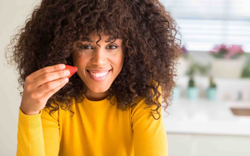 Women eating a strawberry for full body alkalizing and health, Advanced Body Foods